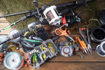 Sport fishing equipment on a table in a studio in a composition, against a wooden background and a fishing net.