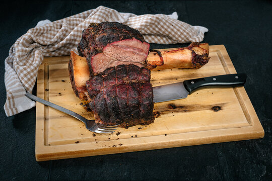 Beef Hammer, Rinderhaxe, Rinderwade, Gabe, Messer, auf Holzbrett auf schwarzem Schiefer, gegrillt, smoken, gesmoked