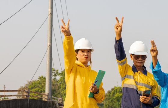 Workers Celebrate Success at Construction Site With Victory Signs During Sunny Day
