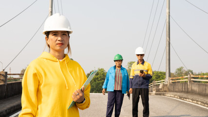 Engineers Inspect Bridge Construction Site in Bright Clothing Under Clear Blue Sky During the Day