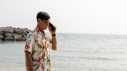Man Talking on the Phone by the Serene Beach at Sunset, Enjoying a Relaxed Moment in Nature During...