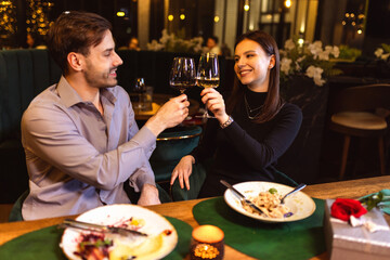 Man and woman toasting with white and red wine in the restaurant while they are on a romantic dinner date.
