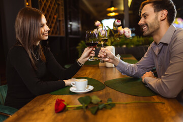 Man and woman toasting with white and red wine in the restaurant while they are on a romantic dinner date.
