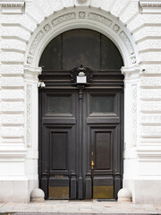Empty double door close-up in an old town in Europe. Dark wooden entrance doors and a bright exterior wall. Close-up of the historical facade.