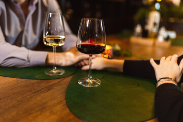 Couple on a romantic date. They drink wine and hold hands.