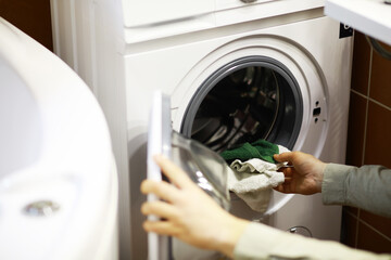 Person Loading Clothes into a Modern Front-Loading Washing Machine