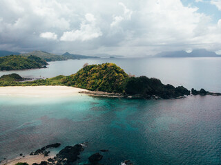 Aerial shot of Stunning Coastline, white sand beach with blue and turquoise crystal clear water, filled with palm trees and small islands off shore. Dream Tropical Island Destination.