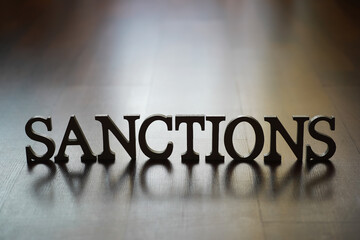 Sanctions Word Sign Reflecting on Hardwood Floor - Economic Penalty Concept