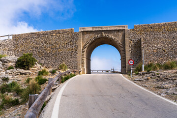 Stone arch on winding Sa Calobra mountain road leading to Mallorcas picturesque coastline. Unique...