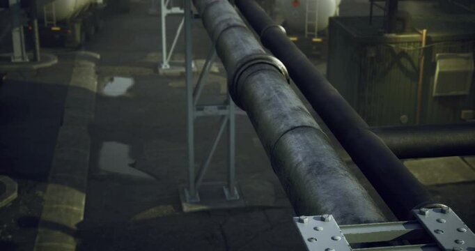 A large pipeline runs parallel to several industrial tanks at a transport facility. The area appears busy and is designed for the efficient movement of materials in an industrial setting.