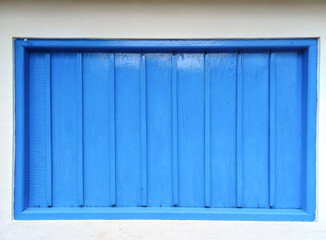 Blue wooden window with closed shutters and white wall of java house in Indonesia