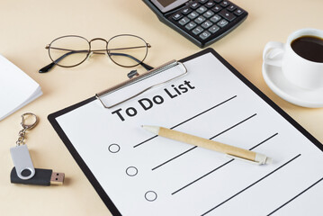 to do list on clipboard with office supplies, isolated on beige background