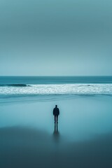 A solitary man stands on a tranquil beach, surrounded by mist, reflecting on the vast ocean ahead.