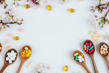 Colorful vitamins and supplements arranged on wooden spoons with floral accents.