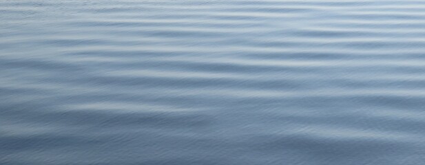 Ripples on light blue smooth water surface as a background