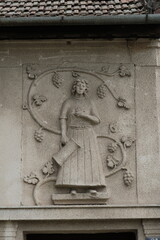 Stone bas-relief of a woman with grapevines, symbolizing viticulture, on a historic facade in Petrovaradin, Serbia. Reflects rural heritage, local tradition, and wine culture of the region.