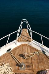 Punkt widokowy z przodu jachtu na spokojnym morzu z widocznym pokładem z drewna tekowego  © Kacper
