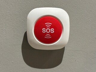 A red emergency alert button is mounted on a neutral wall in Valencia, providing a means for...