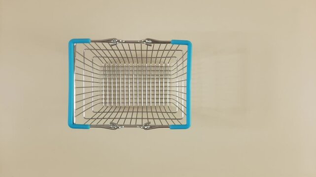 Blue silver empty shopping basket appears and disappears on a light background, top view, stop motion animation