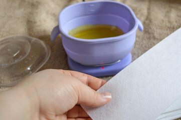 purple wax warmer containing melted yellow wax white waxing strips home professional waxing session hair removal treatments beauty skincare tutorial salon spa services removal kits waxing accessories