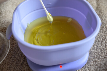purple wax warmer containing melted yellow wax white waxing strips home professional waxing session...