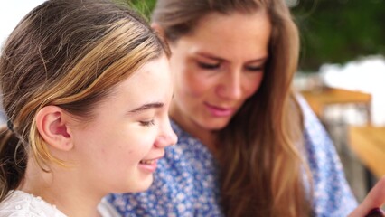 Fototapeta premium Mother Daughter Smartphone Outdoors: Bonding, sharing, technology casual outdoor moment happy family using smartphone.