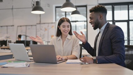 Fototapeta premium A couple sitting together at a table using a laptop, possibly working or browsing