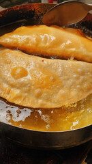 Two chebureks are fried in boiling vegetable oil