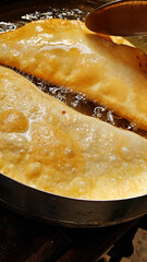 Two chebureks are fried in boiling vegetable oil