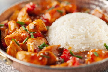 Chicken fillet in sweet and sour sauce with paprika. Rice side dish.