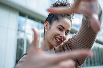 Young woman framing her face with hands and smiling