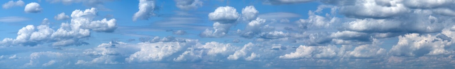 Fototapeta premium Many cumulus clouds float across the blue sky. Sunny panorama with clouds. Heavenly landscape.