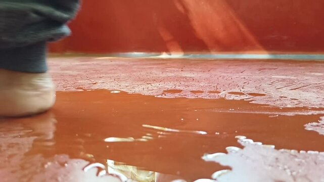 Foot slip on water spilled on wet slippery floor surface. extreme closeup slow motion side view. Leak, bad plumbing, bathroom liquid accident concept.