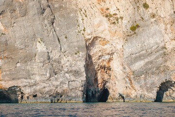 Visitors enjoy the stunning beauty of Greek cliffs by the sea, with rich textures and colors reflecting the summer sun. The tranquil waters invite exploration and adventure