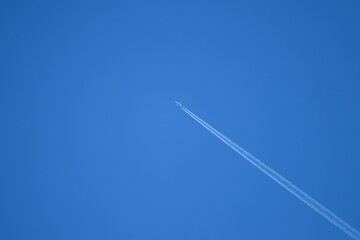 An airplane flying at high altitude leaving its trail in a blue sky.