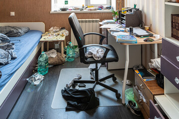 Clutter mess trash and dirt in a 15-16 year old teenage boy's room with scattered belongings, laundry and textbooks