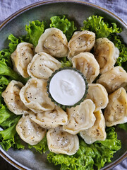Dumplings with sour cream in an iron plate on a gray background