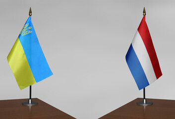 Tabletop flags of Ukraine and Netherlands on stands on a gray blurred background