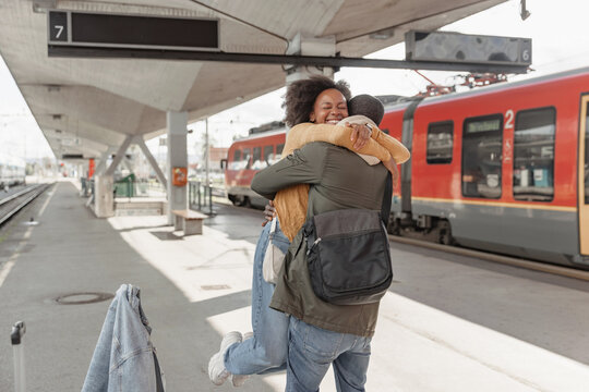 African American couple meeting at a railway station near arrived train, expressing excitement for their upcoming journey together.