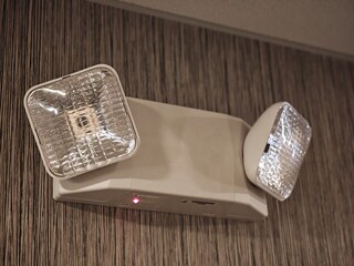 Emergency lighting fixture illuminating against a textured background  