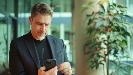 Businessman using phone in office. Serious middle aged man in business casual, Entrepreneur working...