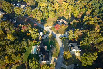 View from above of expensive residential houses between yellow fall trees in suburban area in South...