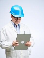 Middle age engineer in lab coat and hard hat. Scientist, architect with tablet. Mid adult, mature age man, happy smiling. Portrait isolated on white.