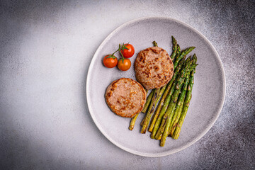 Grilled turkey burgers or cutlets and green asparagus on a plate, top view. Healthy balanced food. High quality photo