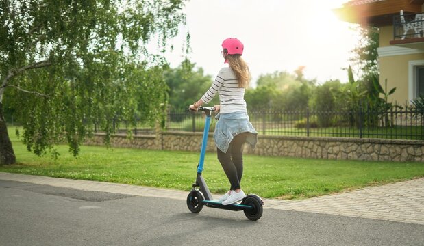 Happy woman driving e-scooter, e-roller, smiling, having fun. Transportation by micro-mobility electric personal vehicle.
