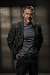 Casual mid adult man standing. Portrait of happy middle aged male entrepreneur in 50s with gray hair, smiling. Confident businessman in business casual on gray background.
