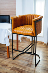 A stylish brown leather bar stool is elegantly positioned in a cozy dining room right next to a...
