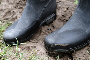 Worn Black Rubber Boots in Mud &ndash; Heavy-Duty Footwear for Outdoor Work and Farming