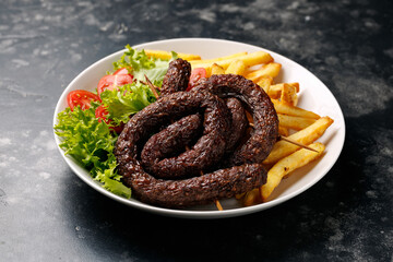 Roasted pork, beef sausages with french fries and vegetables. Snail round sausage