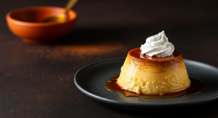 Delicious caramel flan dessert with whipped cream on dark plate